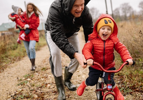 Dad pushing son on a bike while camping